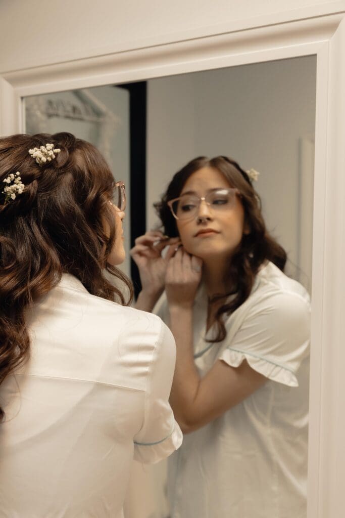 The bride getting ready in the mirror putting her earrings on