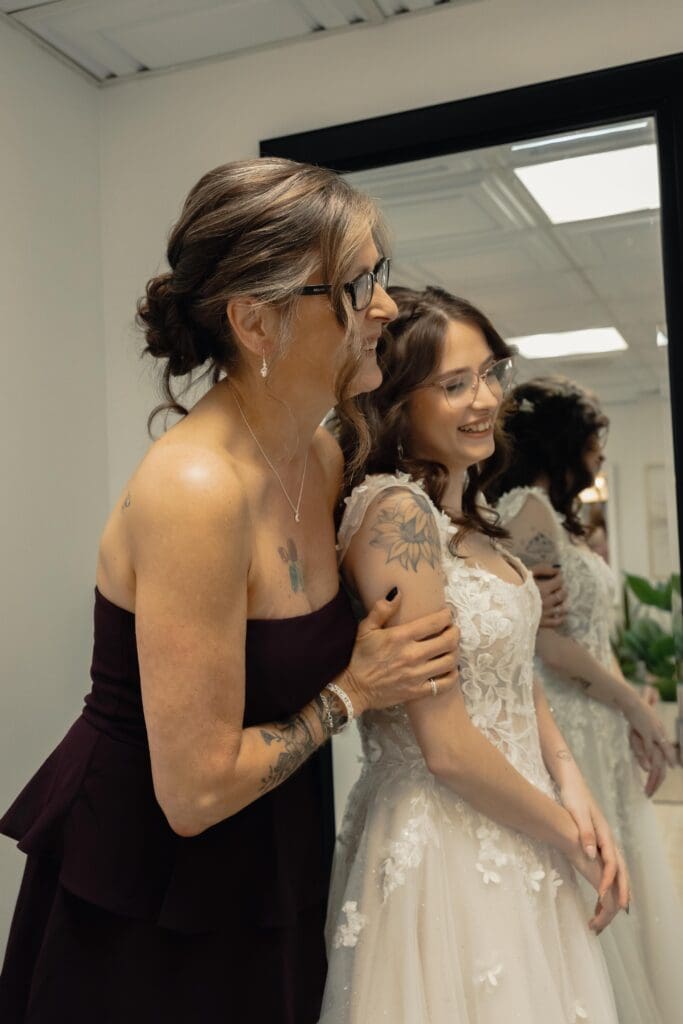 The bride smiling with her mother in the mirror after getting fully ready for her wedding day