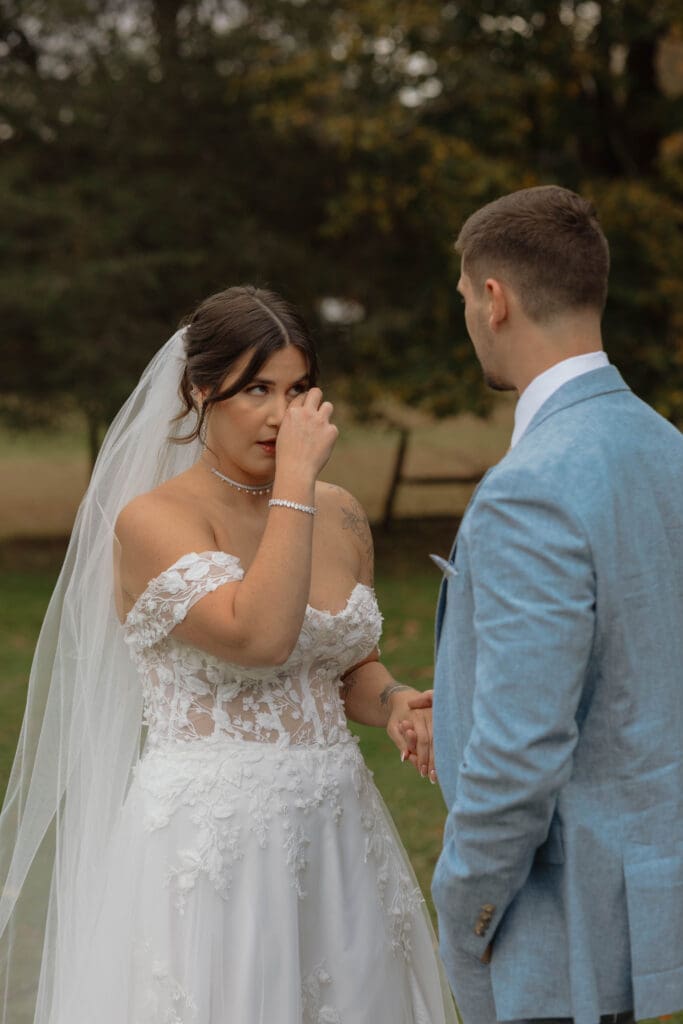 A soon to married couple after their first look and the bride wiping a tear from her eye
