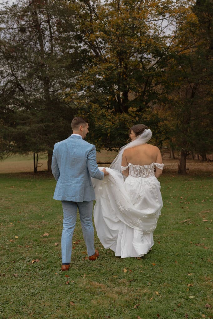 A soon to married couple after their first look walking away with the groom holding the dress train