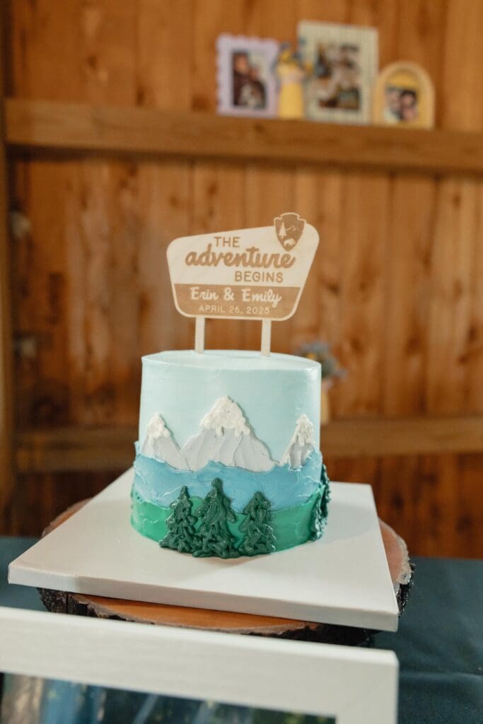 A mountain themed wedding cake saying the adventure begins